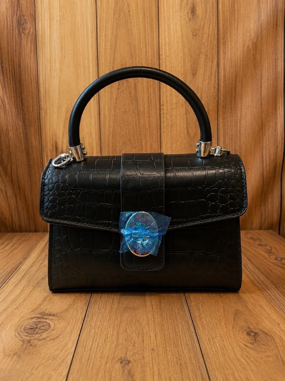 Black crocodile-textured structured handbag featuring a rounded top handle